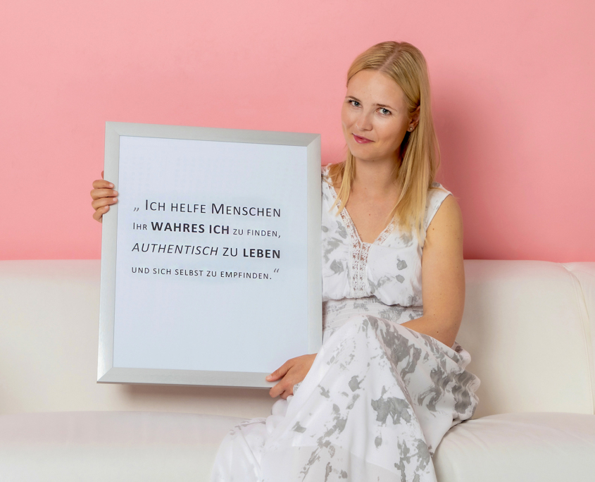 Bianca Rammer sitzend auf einer Couch mit einem individuellem Gedicht in einem Bilderrahmen